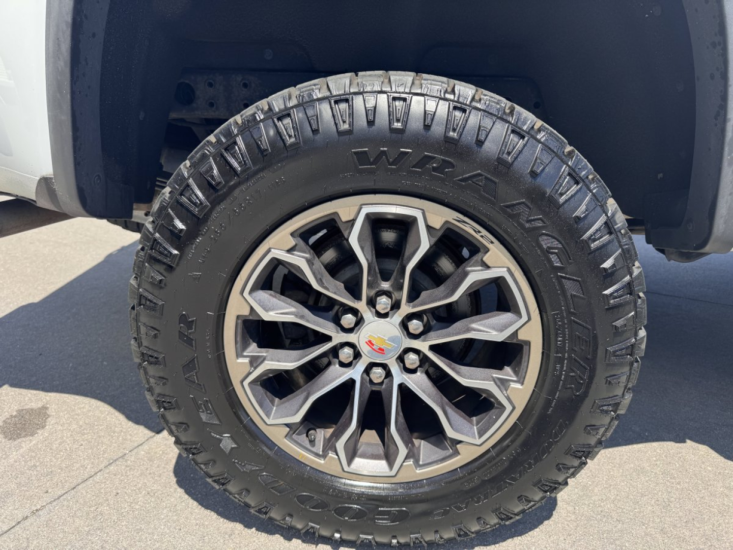 Wheel and tire assembly of a 2018 Chevrolet Colorado with a multi-spoke alloy rim and Goodyear Wrangler Dynamic tire, showing the Chevrolet bowtie center cap.
