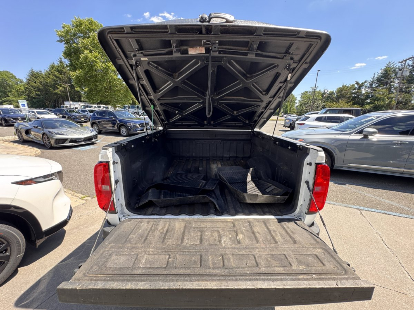 Truck bed of a 2018 Chevrolet Colorado with tailgate down and raised bed cover in a dealership lot.