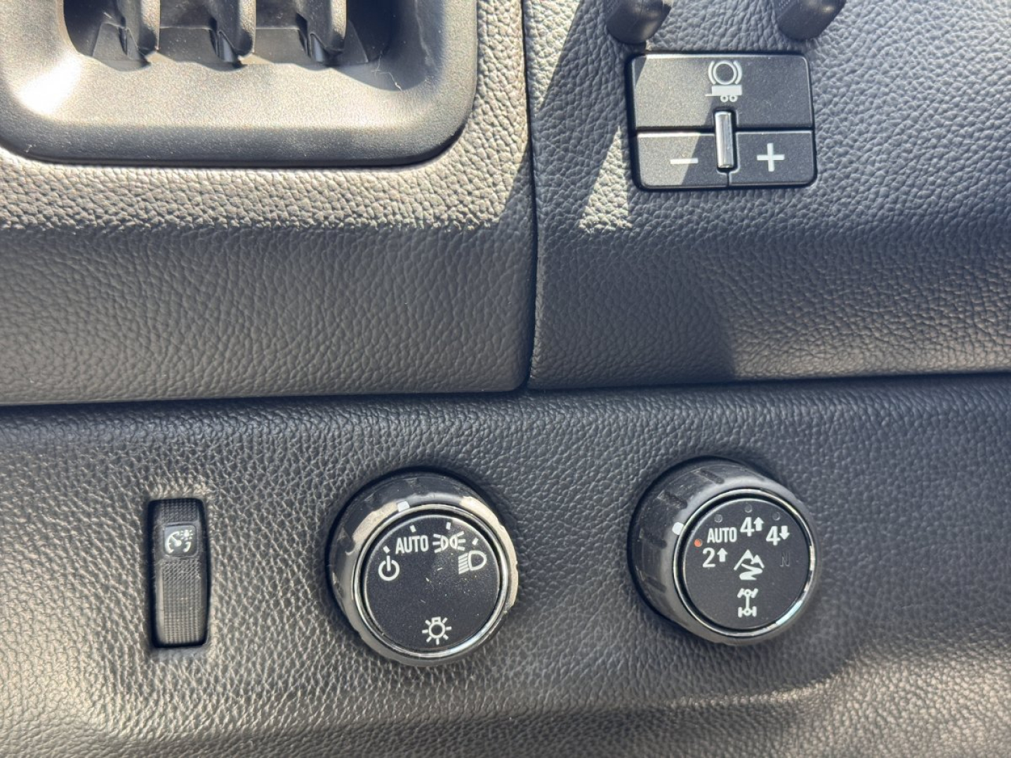 Dashboard controls and knobs; round headlight and four-wheel-drive switches labeled AUTO, 4x4, 2h, 4h, 4L; small switch on left; textured black plastic.