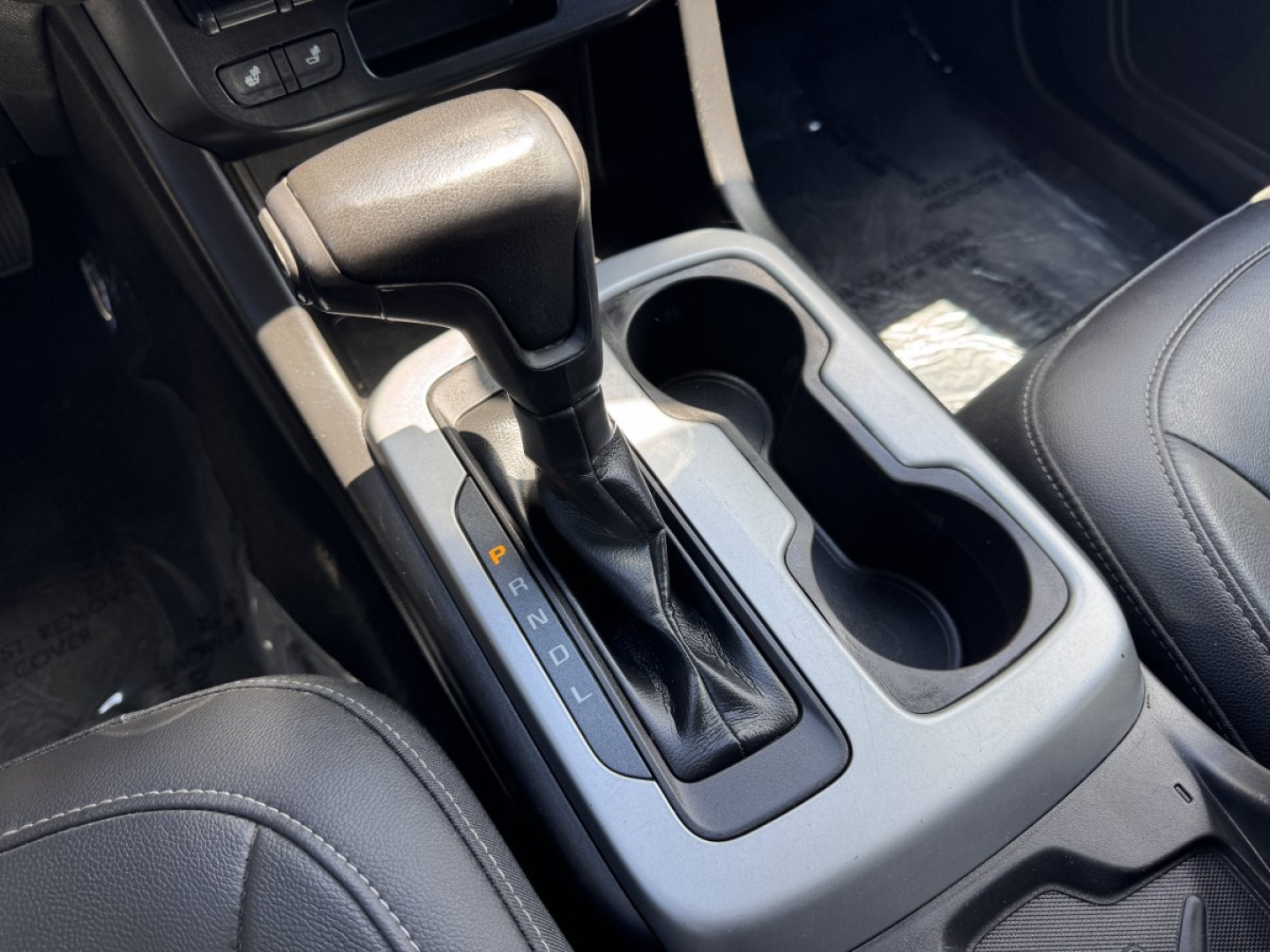 Interior of a Chevrolet Colorado with automatic transmission gear shifter showing PRNDL and cup holders.