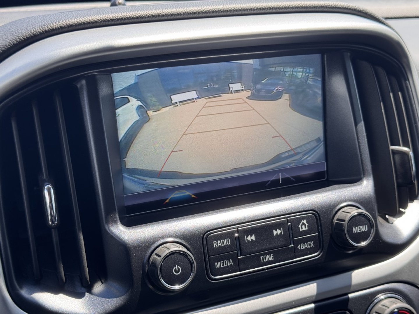 Chevrolet Colorado infotainment system showing rearview camera display with parking guidelines in an angled daytime lot.