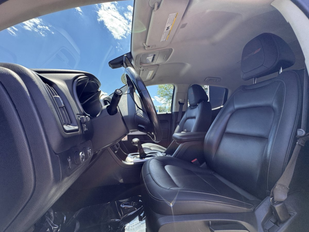 Chevrolet Colorado interior front cabin showing black leather seats and dashboard view from driver door open.