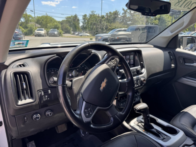 Chevrolet Colorado interior showing steering wheel with Chevy emblem, dashboard, center console, and gear shifter.