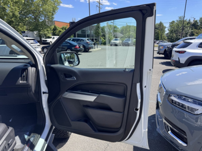 Chevrolet Colorado 2018 truck interior door panel viewed from open front passenger door in a dealership lot; visible window, side mirror, and exterior white paint.