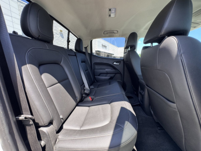 Chevrolet Colorado interior rear seating area showing gray cloth seats, rear bench with three seat belts, door panels, and front passenger seat in view.