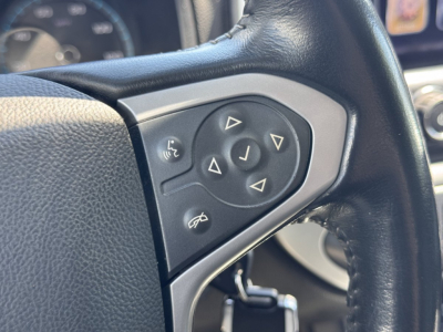 Steering wheel with control pad showing navigation arrows and phone icons on a Chevrolet Colorado interior.