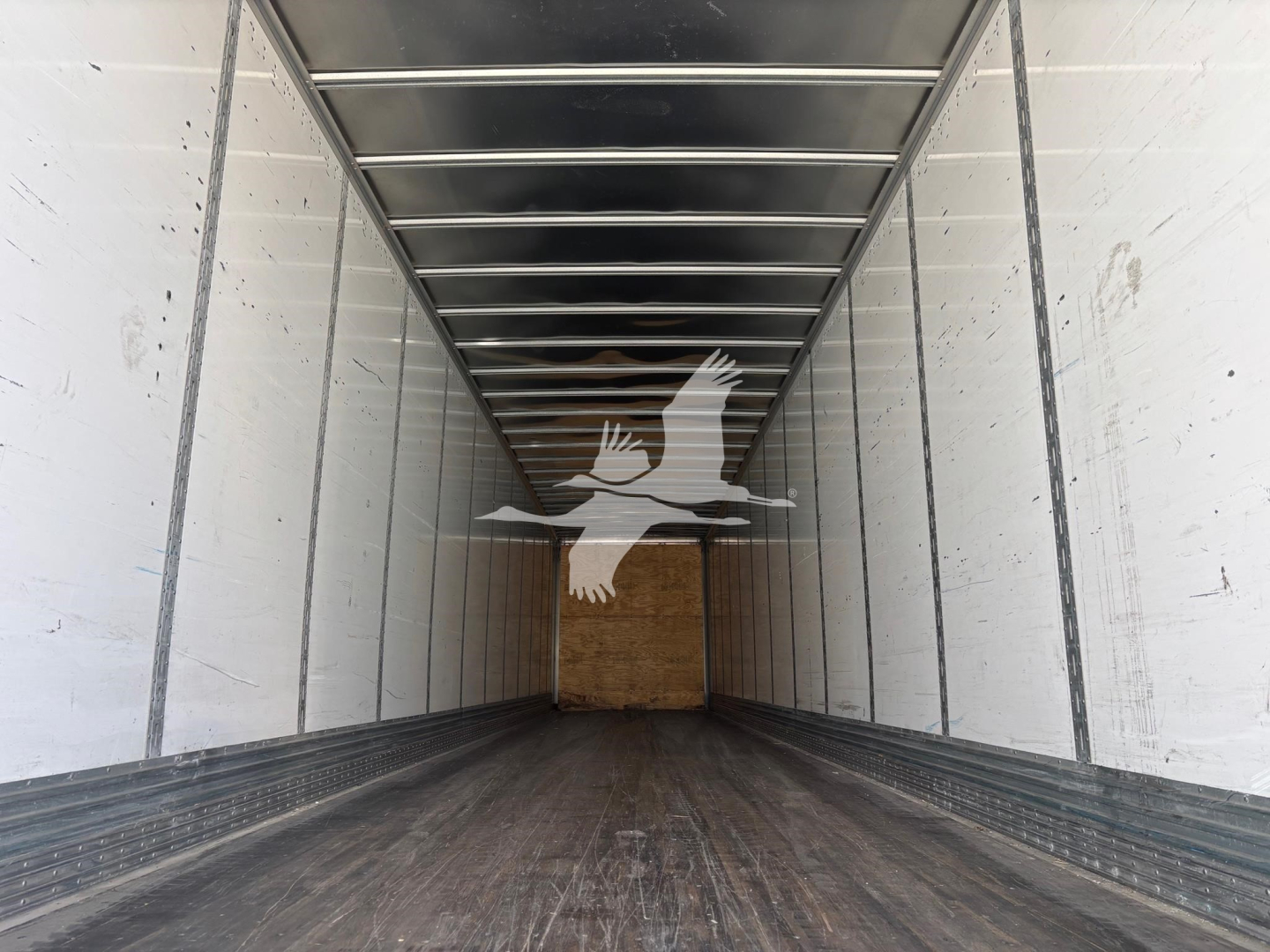 Trailer interior showing long van trailer with metal side rails and wooden rear door, Vanguard branding watermarked.