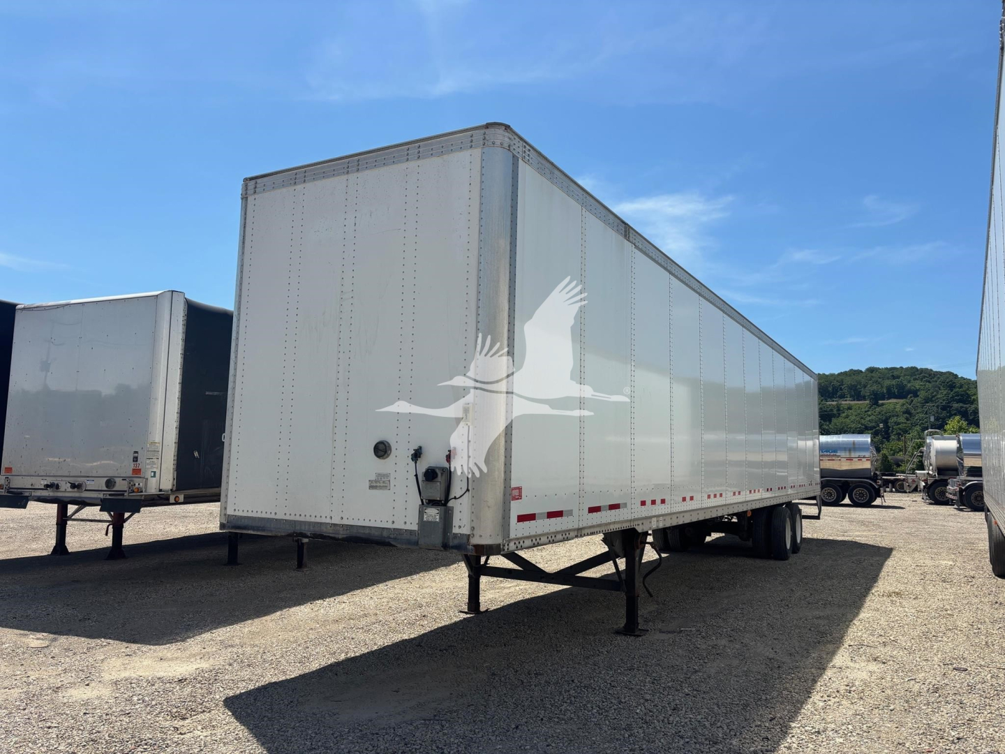 Trailer side view showing enclosed aluminum cargo trailer with V-nose front and landing legs, Vanguard logo on door