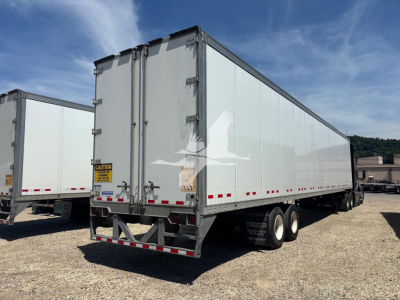 Vanguard trailer showing dual-axle rear with closed vertical doors and safety stickers.