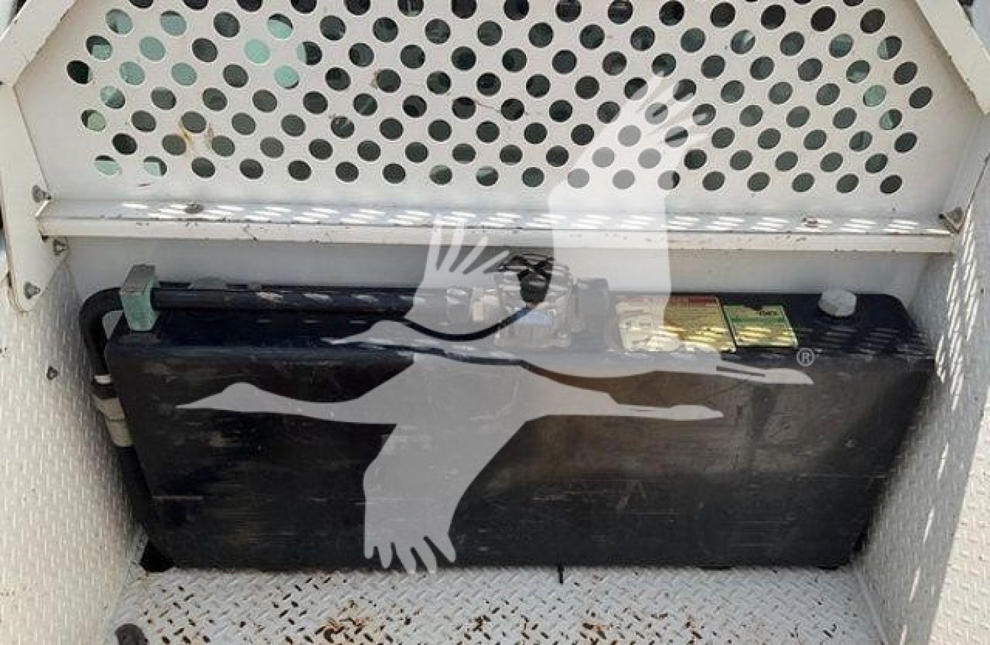 Tray area showing a large black battery under a perforated metal panel.
