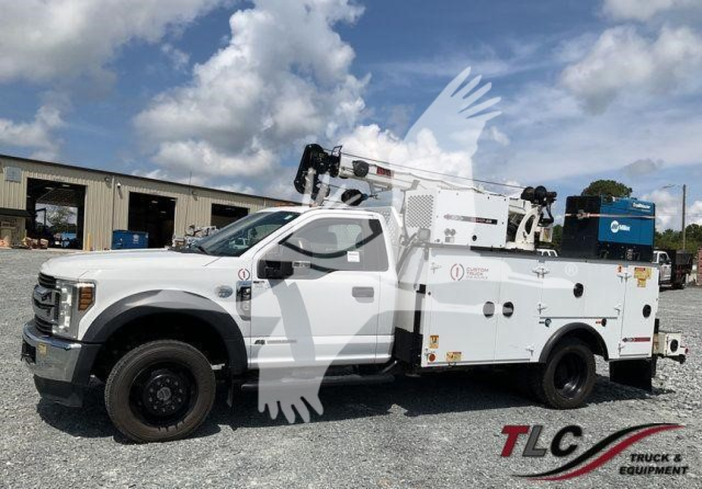 Ford F-550 utility/service truck with bucket and tool compartments, side view showing equipment compartments and crane attachments.