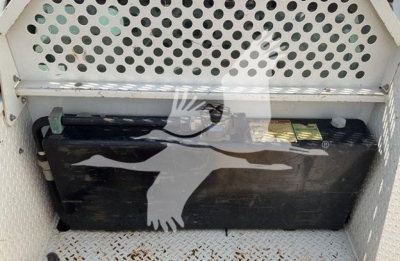 Tray area showing a large black battery under a perforated metal panel.