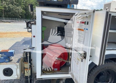 Ford F-550 utility truck side compartment open showing a red fire extinguisher and control panel inside.