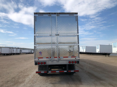 Rear view of a new Utility 3000R W trailer in a lot with diamond plate doors and taillights.