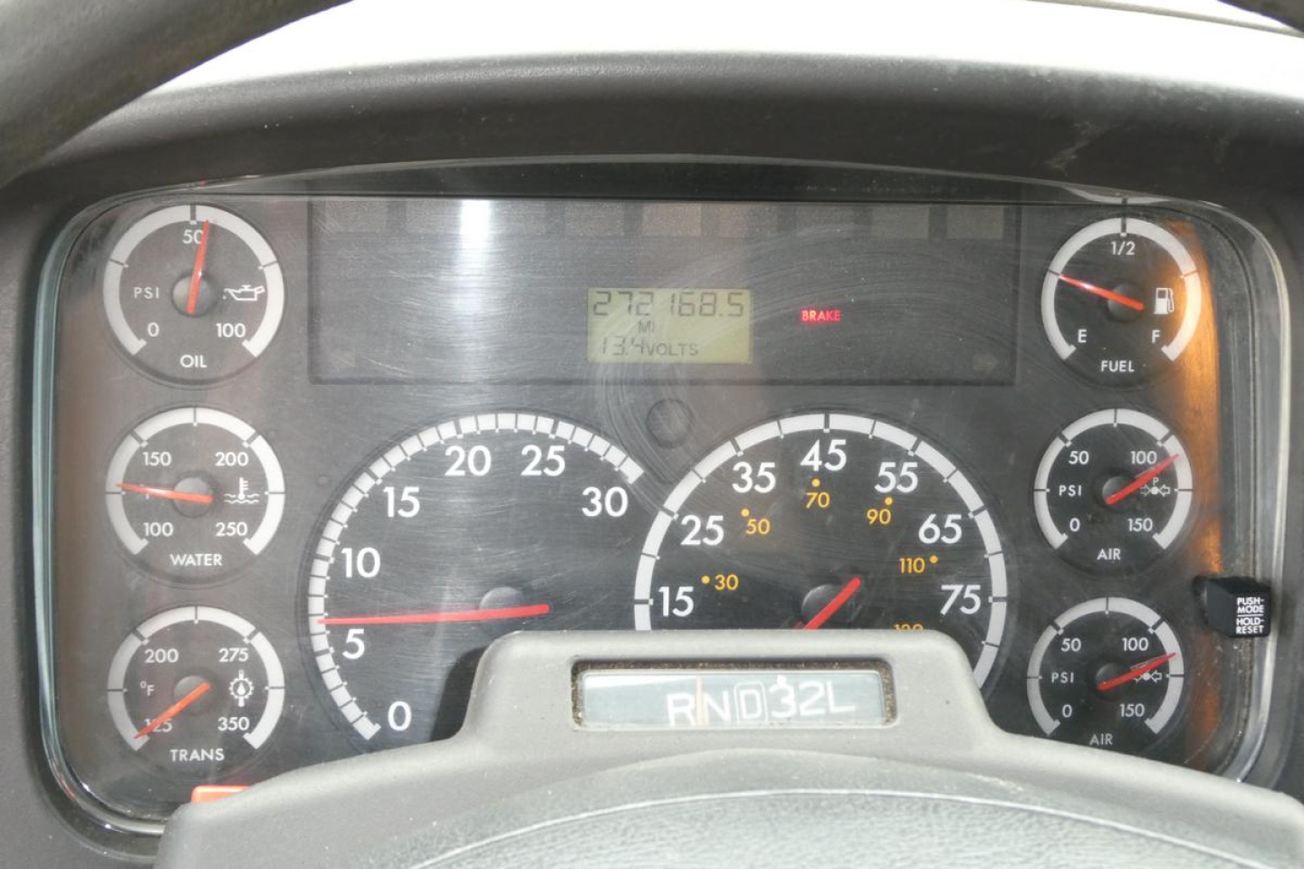 Dashboard of Freightliner M2 106 showing gauges and digital display with numbers. Visible: RND 32L on gear shifter plate. Various gauges including oil, water, fuel, air, voltmeter, and a central digital display reading 272168.5 and 13270 vo
