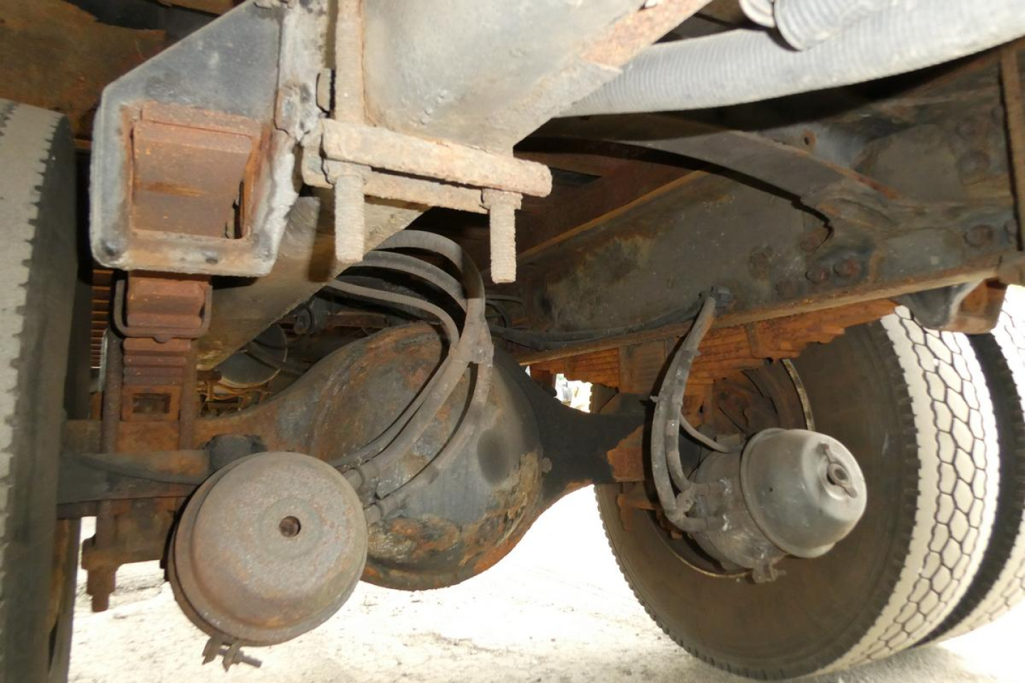 Freightliner M2 106 undercarriage showing drivetrain components including differential housing and axle assemblies with suspension and drum brake hubs.