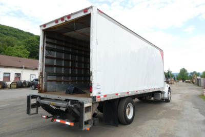 Box truck cargo area of a 2007 Freightliner M2 106 in a dispatcher lot, with empty interior cargo space and reinforced steel ribs visible; rear undercarriage and rear bumper assembly in view.