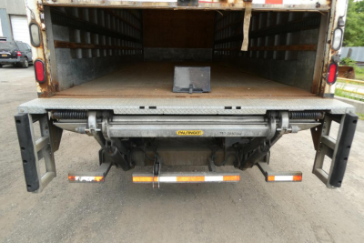 Truck rear showing Holm-style tailgate underbed with Palfinger hydraulic system and bumper guards on Freightliner M2 106 box truck.