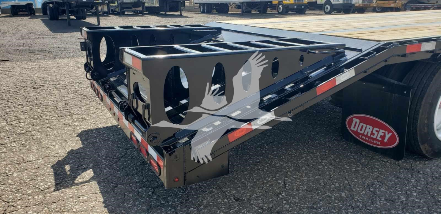 Dorsey beavertail dropdeck trailer rear view showing steel frame with circular cutouts and reflective tape along edge.