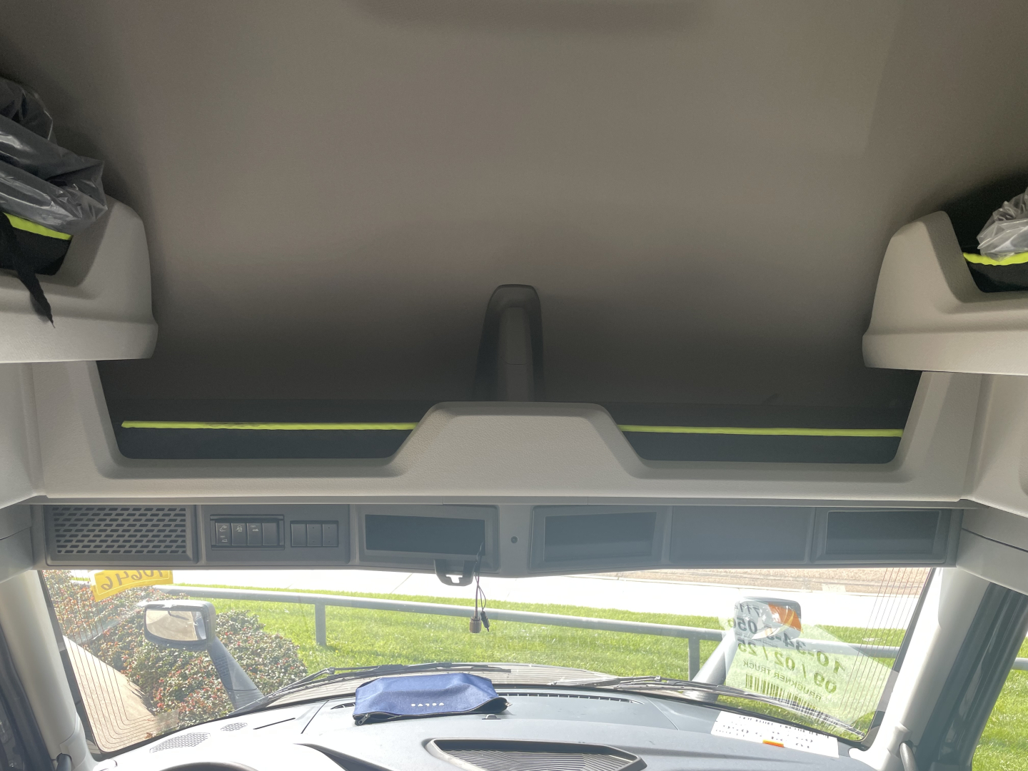 Truck cab interior showing windshield and sun visor area with overhead console and digital displays. Text not clearly legible.