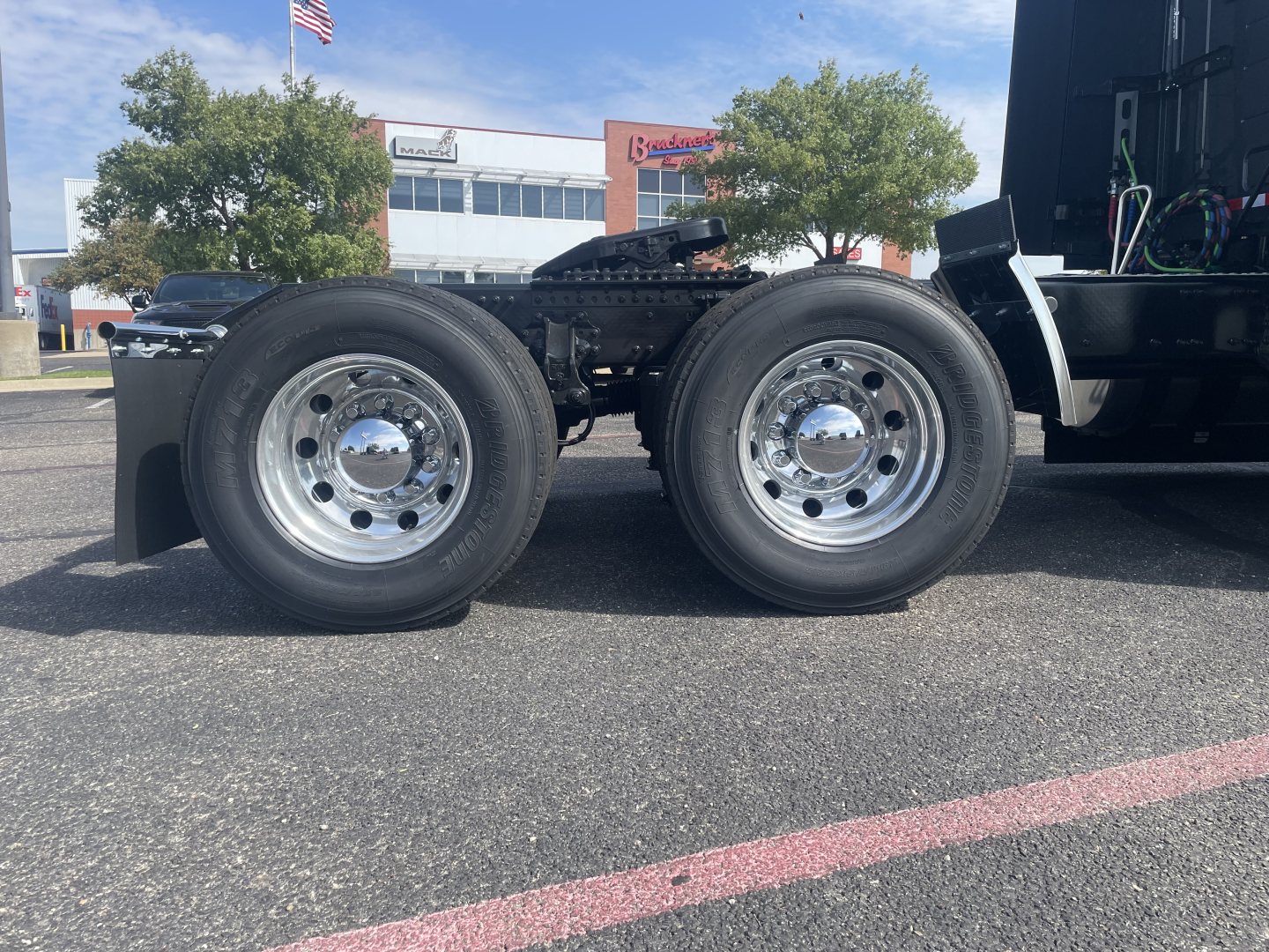 Volvo VNL64T660 tractor (front left view) showing dual rear drive wheels with polished chrome hubs and part of the cab chassis.