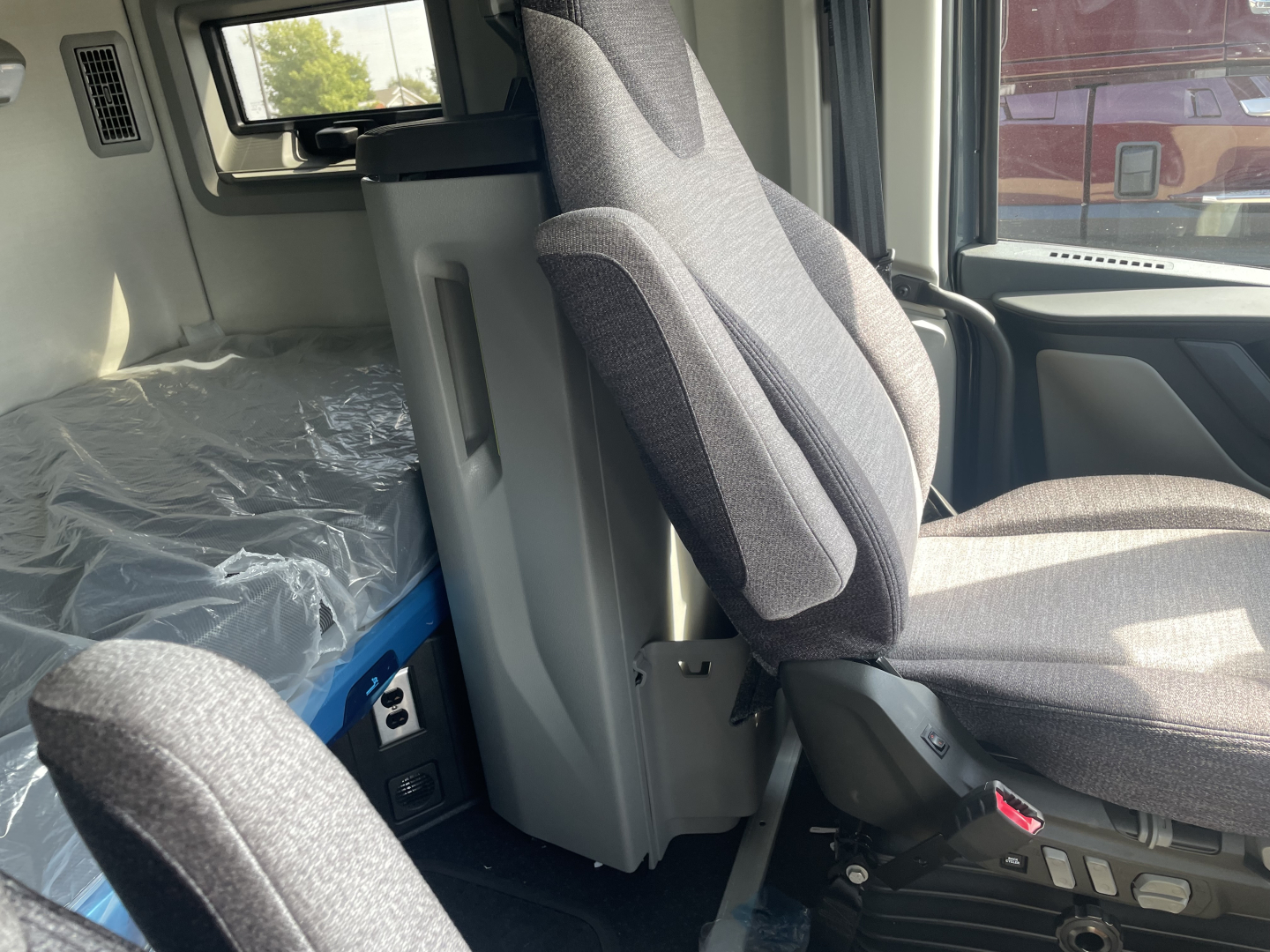 Volvo VNL64T660 truck interior view with driver seat and sleeper area visible, fabric seats, and center console.
