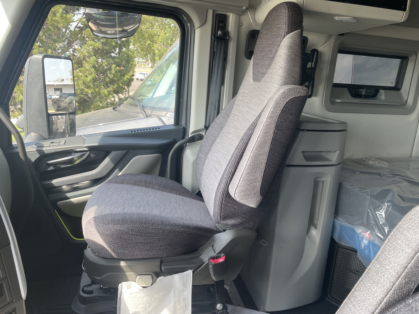 Interior of a new Volvo VNL64T660 truck cab showing driver seat and headset, with storage drawers and cabin area visible.
