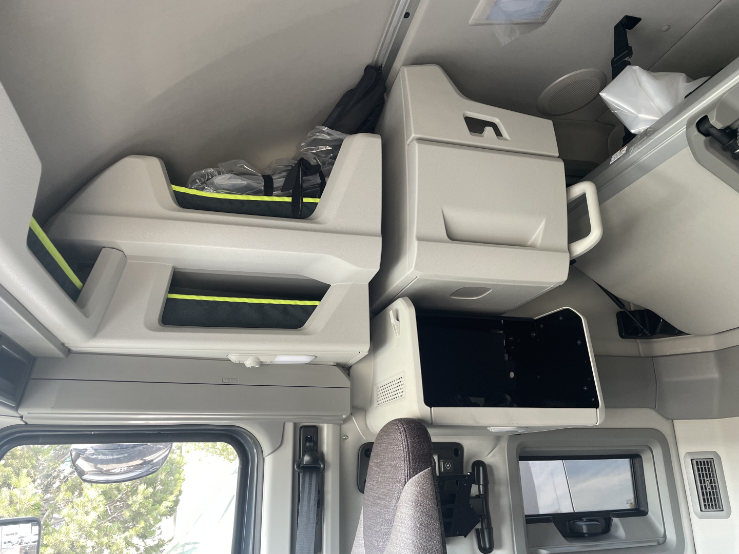 Interior of a Volvo VNL tractor cab showing sleeper area, overhead storage, and control panel with light gray upholstery.