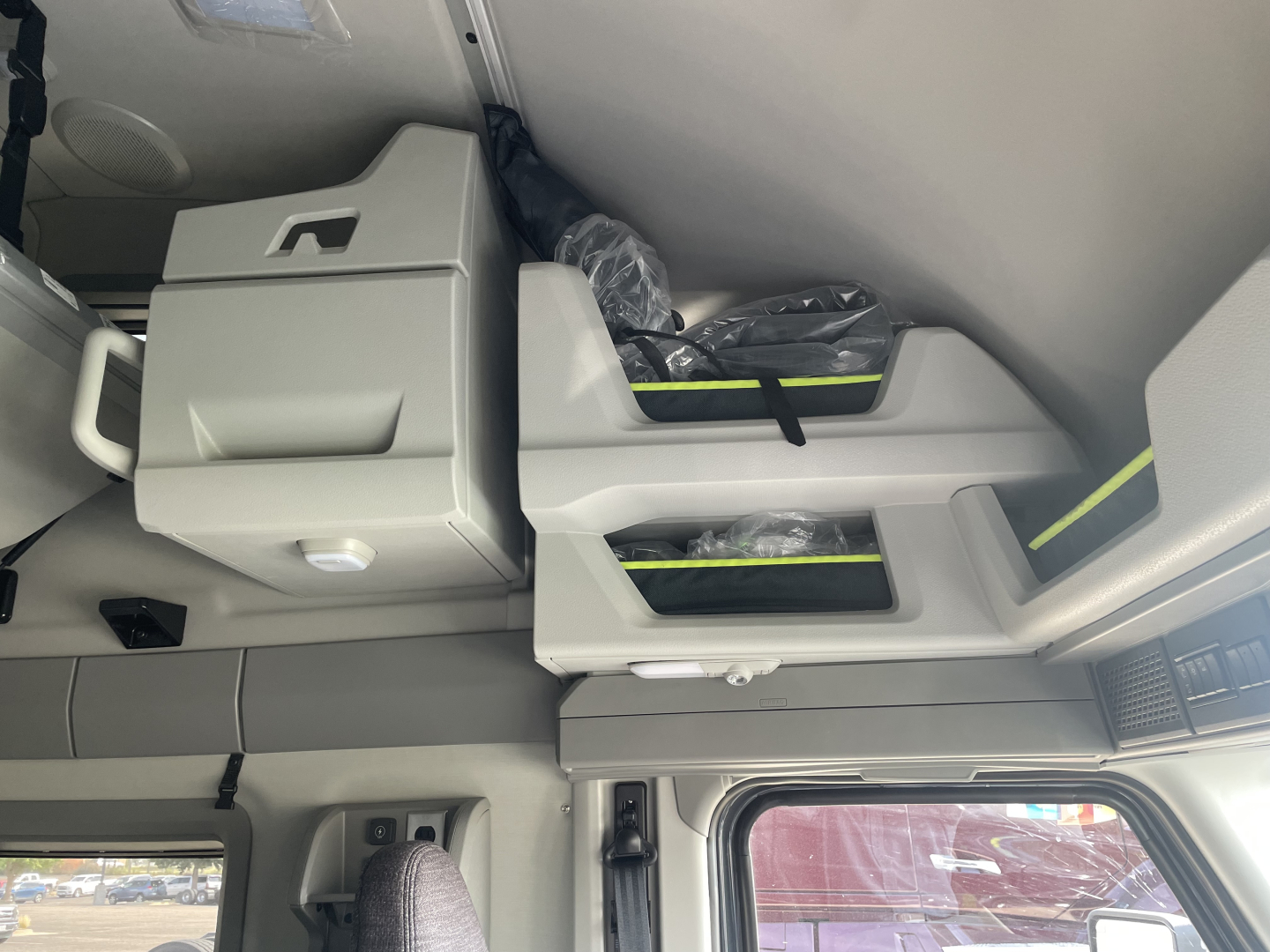 Interior sleeper cab area of a 2026 Volvo VNL64T660 showing storage compartments and seat/console with plastic-wrapped items.