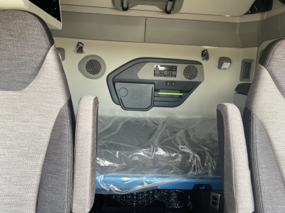 Rear sleeper area of a Volvo VNL truck showing overhead console and control panel, with two seats and a plastic-covered sleeping area.