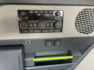 Dashboard controls and storage area in Volvo VNL64T660 cabin showing control panel with numerous buttons, speaker grill on right, and a lime green tray handle.