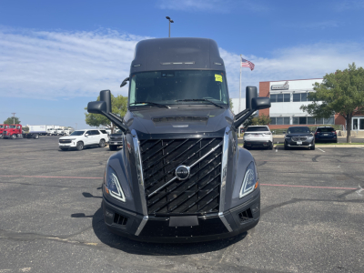 Front view of a new 2026 Volvo VNL64T660 tractor in a dealership lot, showing the distinctive black grille, large windshield, and side mirrors.