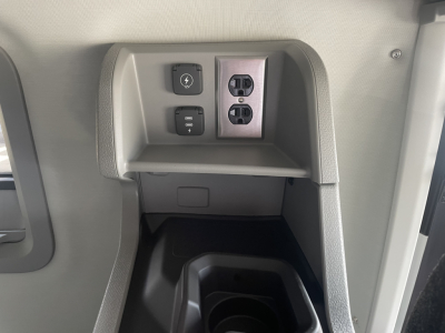 Truck interior center console with power outlet and two USB-style sockets, small cubby, and control switches visible.