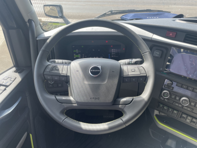 Volvo steering wheel and dashboard inside the cab showing control buttons and a digital instrument cluster.