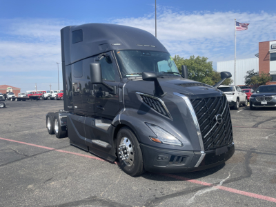 Volvo VNL64T660 truck in a dealership lot, black exterior, sleek aerodynamic cab, front grille, large side mirrors, multiple wheels, daytime