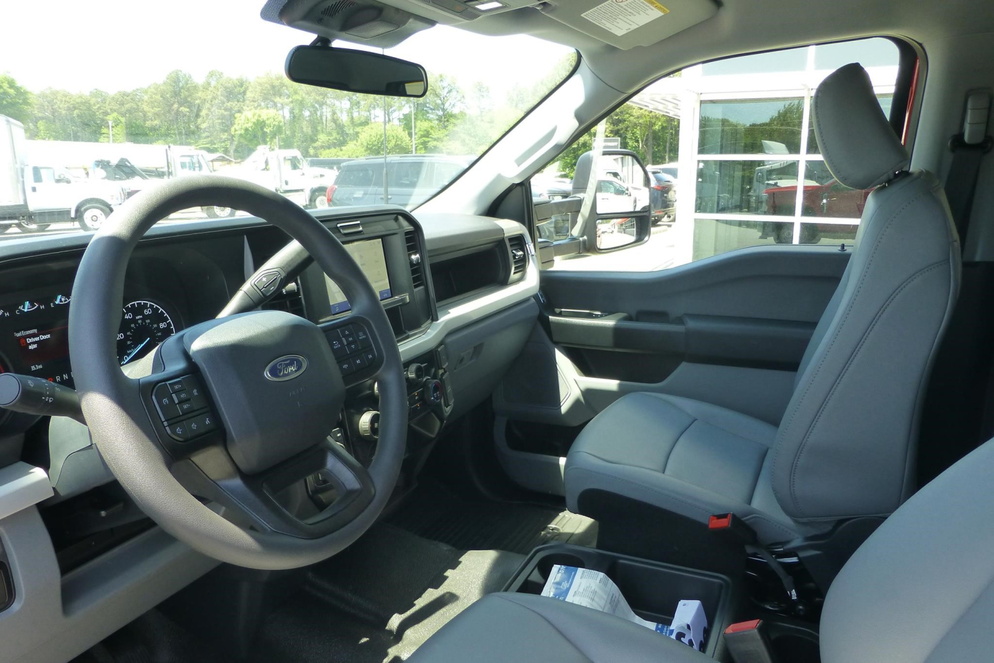 Front interior of a Ford F-250 pickup showing steering wheel, dashboard infotainment screen, and front seats.