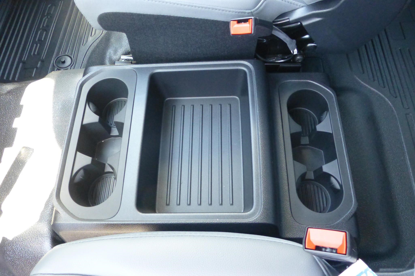 Truck interior center console with cup holders and storage bin in a Ford F-250 Super Duty crew cab.