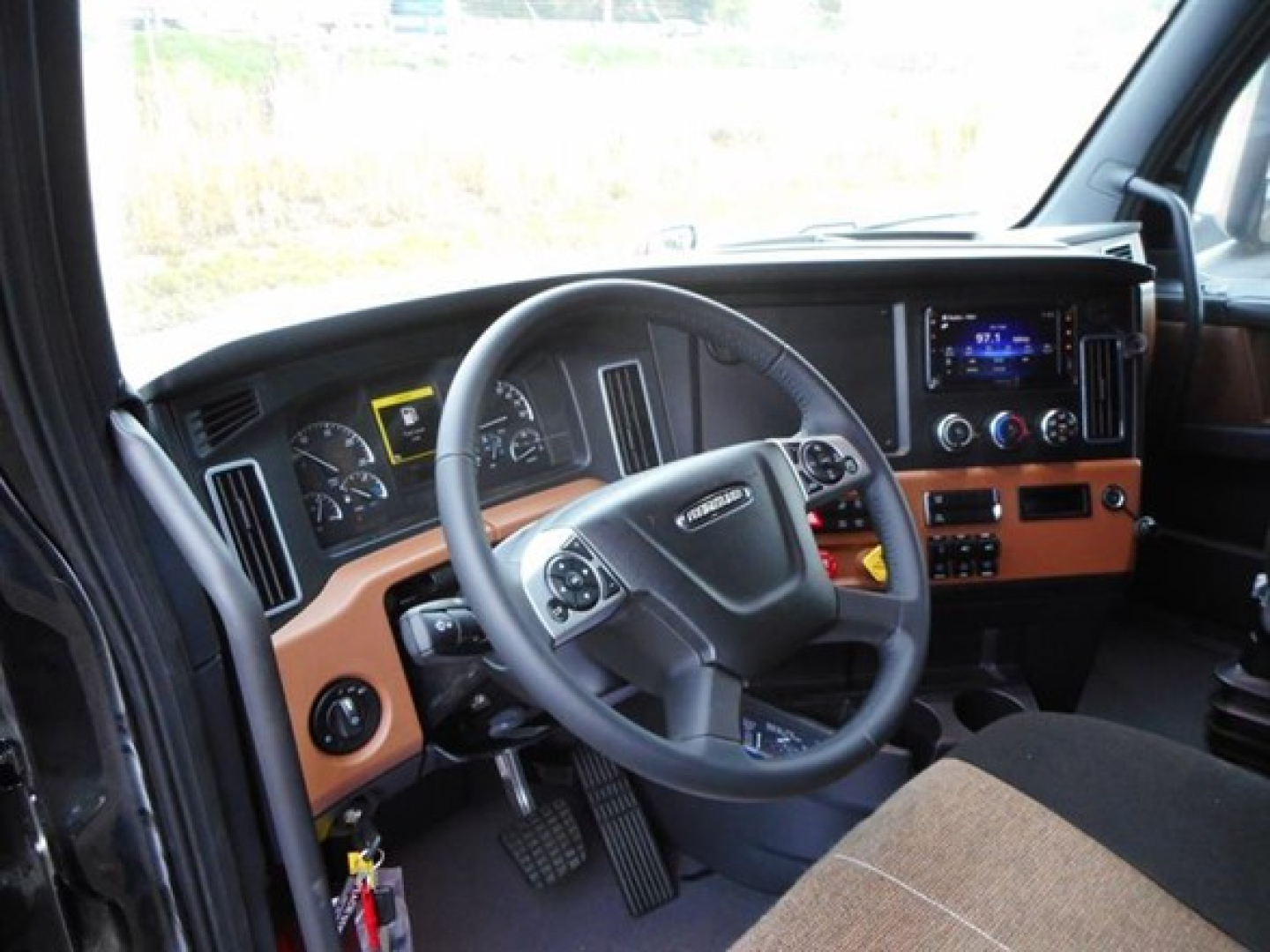 Freightliner Cascadia 126 interior showing steering wheel, dashboard, and center console with digital display.