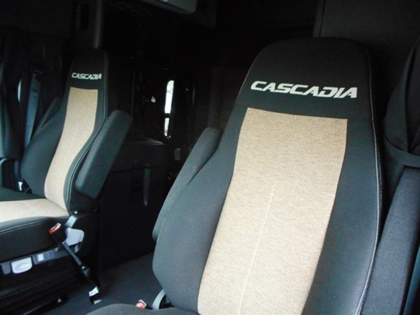 Cascadia truck seats in cabin showing CASCADIA embroidered headrests and beige fabric inserts.