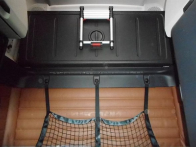 Freightliner Cascadia cab interior with rear storage hatch and brown sleeper mattress visible.