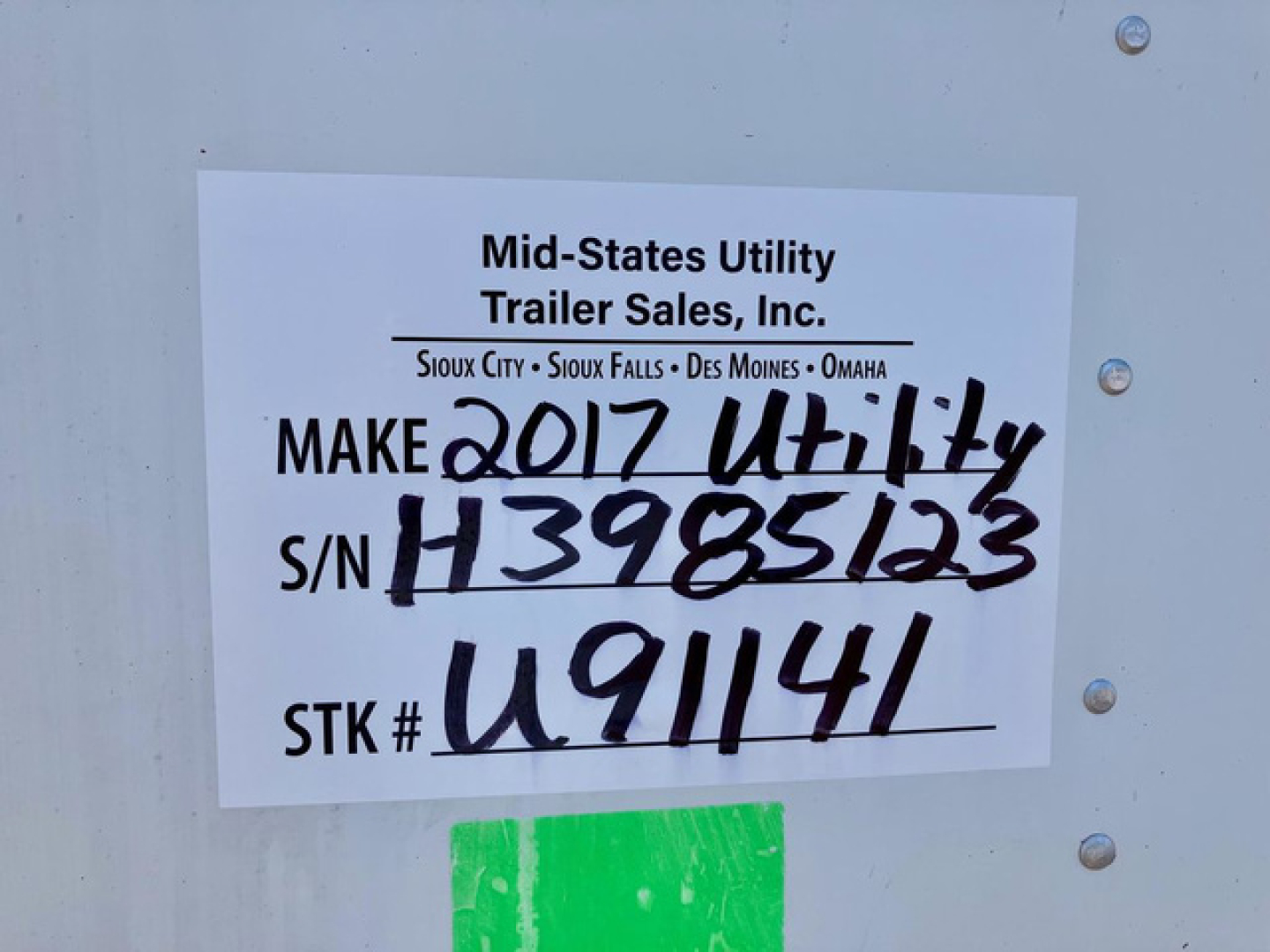 Sign on trailer with handwritten and printed text: ‘Mid-States Utility Trailer Sales, Inc.’, MAKE 2017 Utility, S/N H3985123, S/N H3985123, STK # U91141. Also lists locations Sioux City, Sioux Falls, Des Moines, Omaha.
