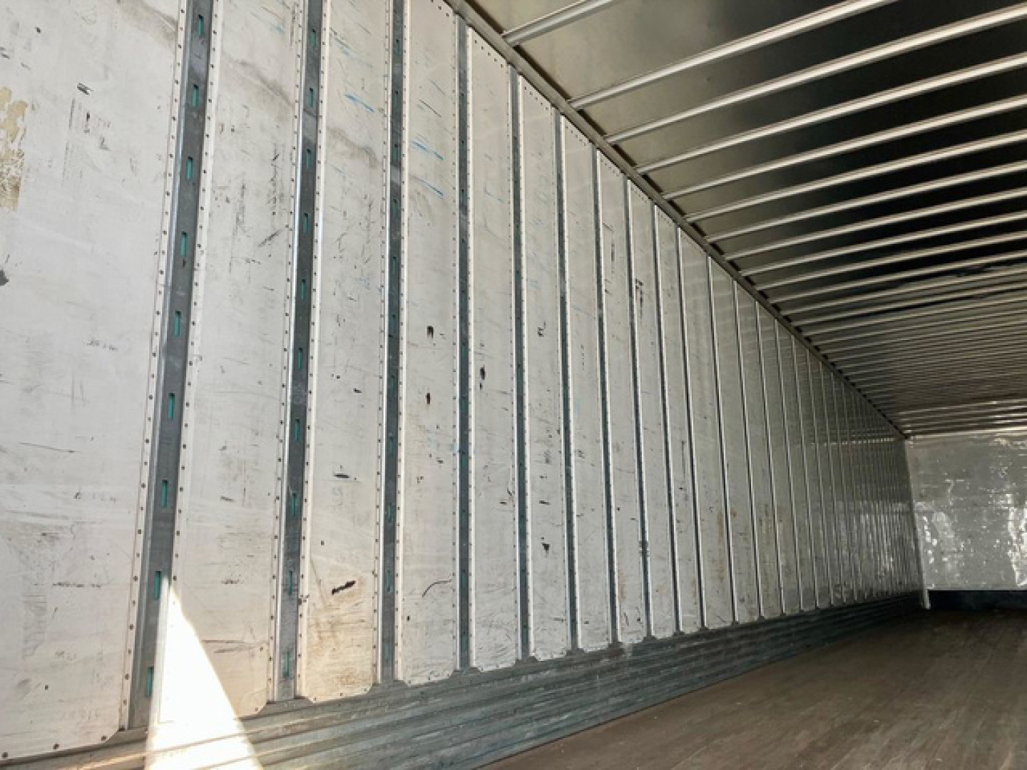 Van trailer interior showing vertical metal wall studs and ribbed ceiling inside an empty cargo area.