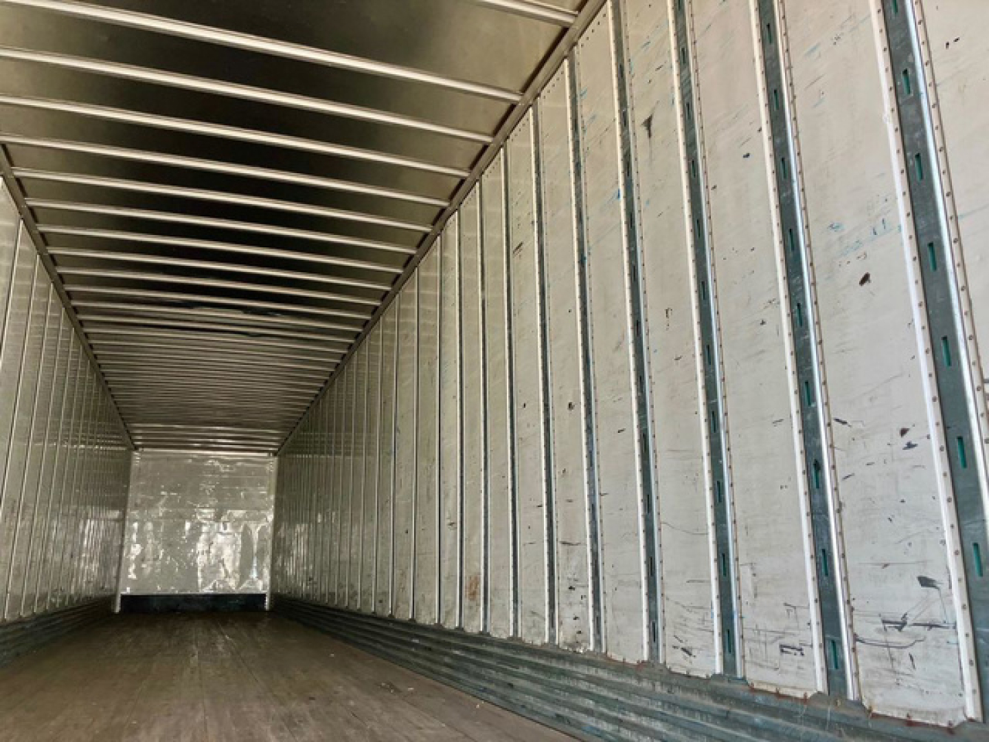 Interior of a used trailer van showing corrugated metal walls and floor with vertical support rails.