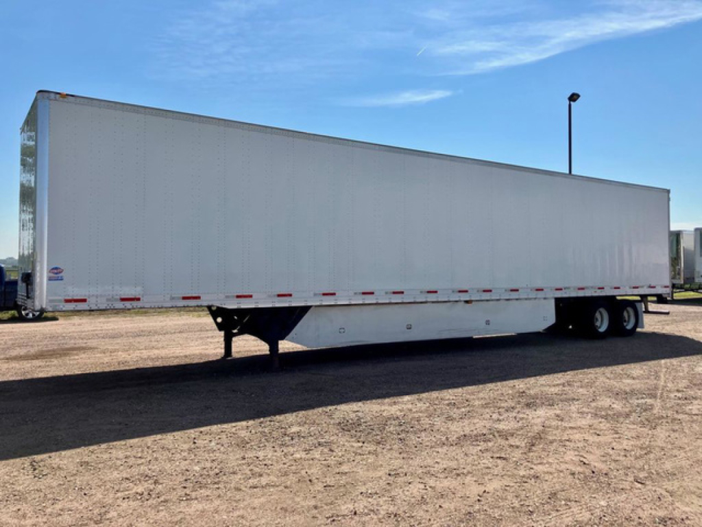 Utility van trailer viewed from side showing long rectangular cargo box with tandem axles at rear and landing gear, white exterior.