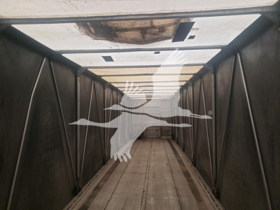 Trailer interior showing a long flatbed trailer withCurtainside design, empty cargo area, light panels along the ceiling.
