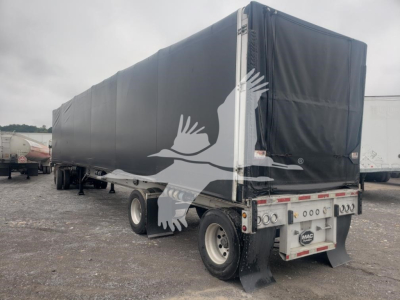 Mac flatbed trailer with black curtain side view showing tarp and rear bumper area; visible text includes MAC trailer plate and rear lights.