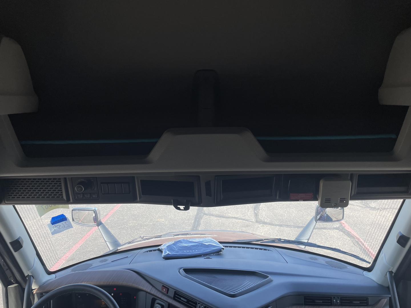 Cab interior of a 2026 Volvo VNL64T860 tractor showing dash area and windshield with reflection, no visible text on components.