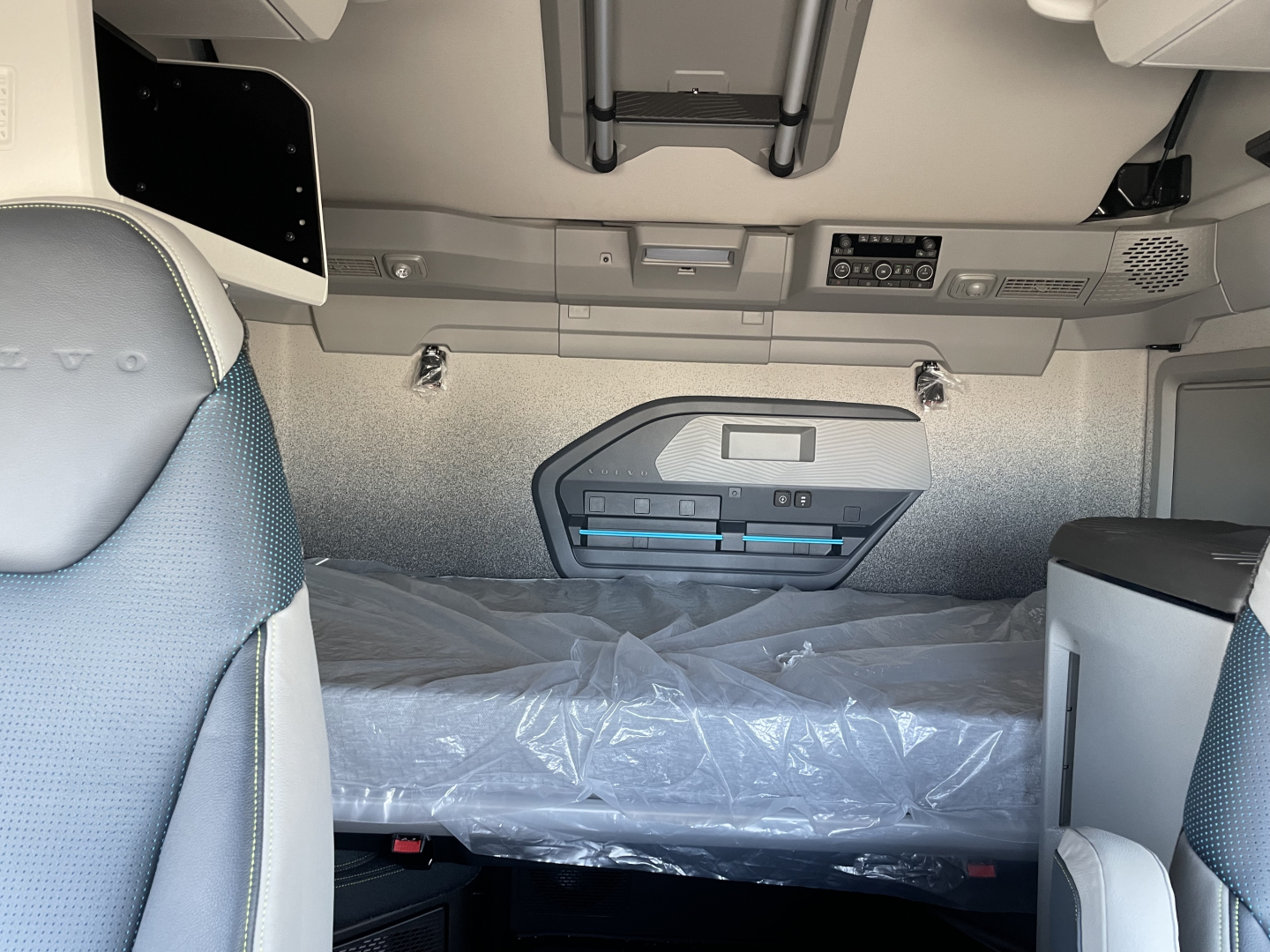 Volvo VNL64T860 cab interior showing sleeper bed area with plastic covering and overhead controls