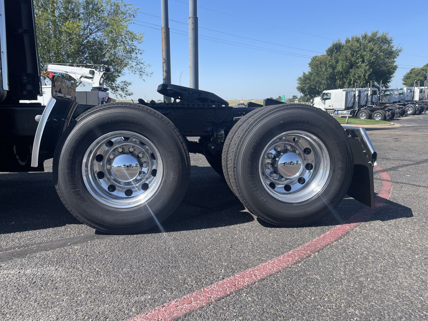 Volvo VNL64T860 tractor dual rear wheels showing chrome rims and black frame with various trucks in background.