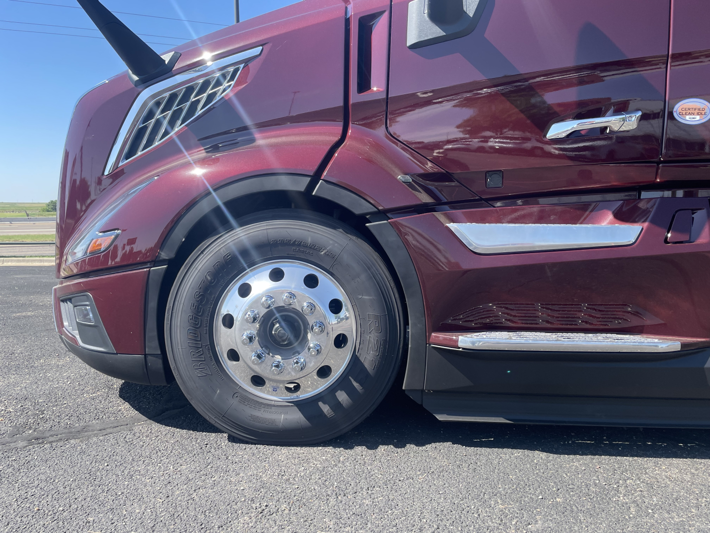 Volvo VNL64T860 truck front quarter showing front wheel, maroon color, cab side mirrors, and chrome accents.
